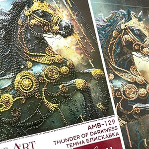 Puede incluir: Primer plano de dos obras de arte detalladas que representan la cabeza de un caballo. Los caballos est&aacute;n adornados con intrincados abalorios en tonos negros, dorados y marrones. El texto "THUNDER OF DARKNESS" es visible en el embalaje.