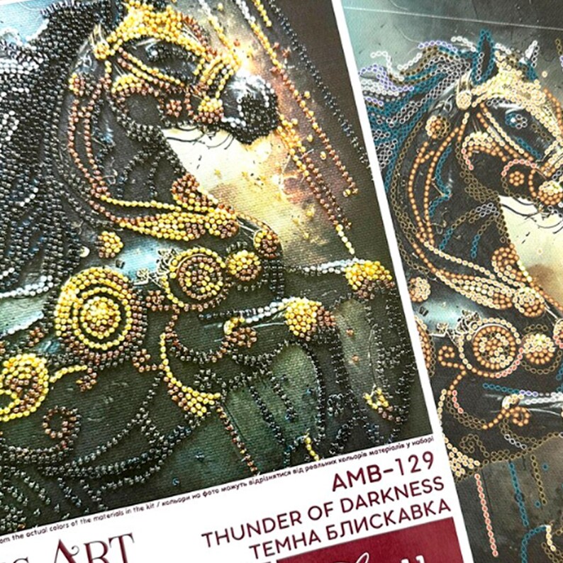 Puede incluir: Primer plano de dos obras de arte detalladas que representan la cabeza de un caballo. Los caballos est&aacute;n adornados con intrincados abalorios en tonos negros, dorados y marrones. El texto "THUNDER OF DARKNESS" es visible en el embalaje.