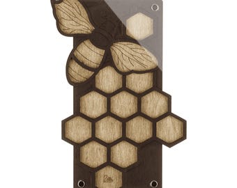 May include: A rectangular wooden wall plaque featuring a dark brown base with a layered light wood honeycomb pattern. A large, detailed wooden bee cutout is attached to the top left. The design includes a clear acrylic overlay and metal hardware.
