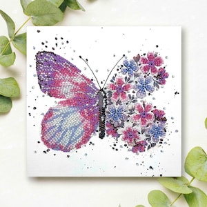 Op de afbeelding: Een paarse en roze vlinder met een wit en blauw patroon op zijn vleugels. De vlinder wordt omringd door roze en blauwe bloemen.