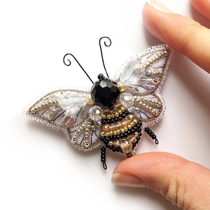 May include: A beaded bee brooch with a black head, gold and black striped body, and clear crystal wings.