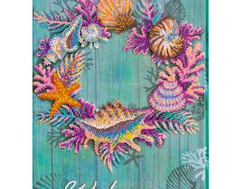 Könnte beinhalten: Ein rechteckiges Wandbild mit einem türkisfarbenen Holzplanken-Hintergrund und einem kreisförmigen Kranz aus perlenbesetzten Muscheln, Seesternen und Korallen in Rosa, Orange und Blau. Das Wort Welcome steht in weißer Schrift unten.