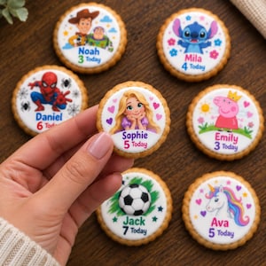 May include: Seven round cookies with scalloped edges, each featuring a different cartoon character and a child's name with their age. Characters include Woody and Buzz, Stitch, Spider-Man, Rapunzel, Peppa Pig, a soccer ball, and a unicorn.