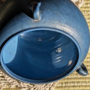 May include: A large, deep blue ceramic bowl with a wide, round opening. The bowl has a smooth, glossy finish and is perfect for serving or displaying.