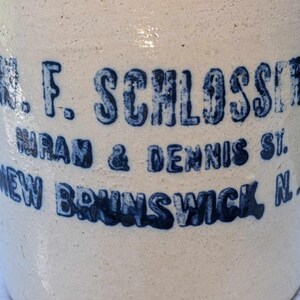 May include: A white ceramic crock with blue lettering that reads "W. F. Schlosser, Wran & Dennis St., New Brunswick, N.J."