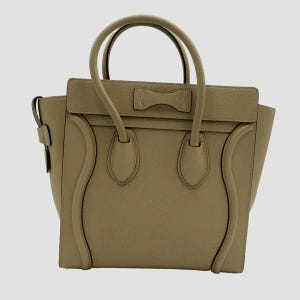May include: A beige leather tote bag with a bow detail on the front. The bag has two top handles and a zipper closure.