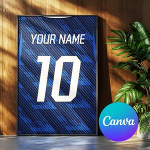 Op de afbeelding: Blauw ingelijst shirt met de tekst "YOUR NAME" boven het nummer "10" in wit. Het shirt heeft een diagonaal streepjespatroon. Het ingelijste kunstwerk wordt tentoongesteld tegen een houten muur met een plant op de achtergrond.