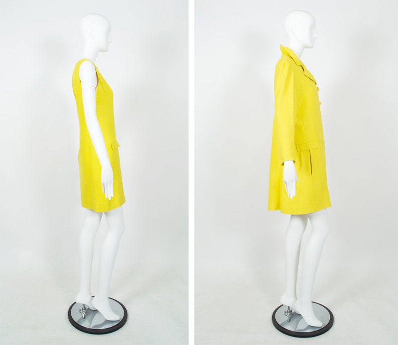May include: A yellow sleeveless dress and a yellow coat with a collar and buttons. Both garments are on mannequins with white skin.