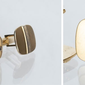 May include: A pair of gold cufflinks with a silver stripe down the center. The cufflinks are square shaped.