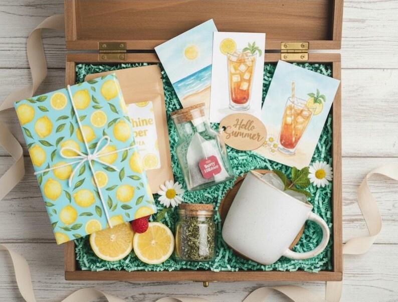 Op de afbeelding: Een houten kist gevuld met zomerse items. Bevat een ingepakt cadeau met een citroenpatroon, ansichtkaarten met ijsthee-illustraties, een witte mok en kleine glazen potjes. De kist is bekleed met groen papier en versierd met madeliefjes.