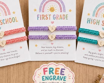 Könnte beinhalten: Drei weiße Präsentationskarten mit Regenbogen-Grafiken und Text, die jeweils zwei geflochtene Kordelarmbänder mit herzförmigen Anhängern halten, welche mit den Buchstaben L, K, A, B, M und E graviert sind. Ein kleines Schild zeigt FREE ENGRAVE.