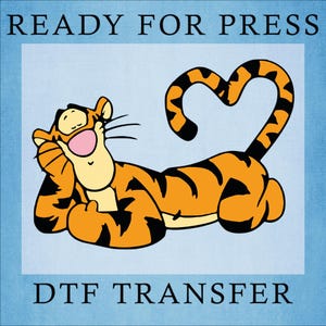 May include: DTF transfer featuring a cartoon tiger in orange and black, with a heart-shaped tail. The tiger is lying down, smiling with its eyes closed. The words "READY FOR PRESS" and "DTF TRANSFER" are printed above and below the image.