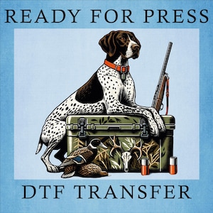 May include: DTF transfer design featuring a hunting dog with a rifle, resting on a green box with hunting-themed graphics. A duck, deer skull, and two shotgun shells are also present. The text "READY FOR PRESS" and "DTF TRANSFER" are at the top and bottom.