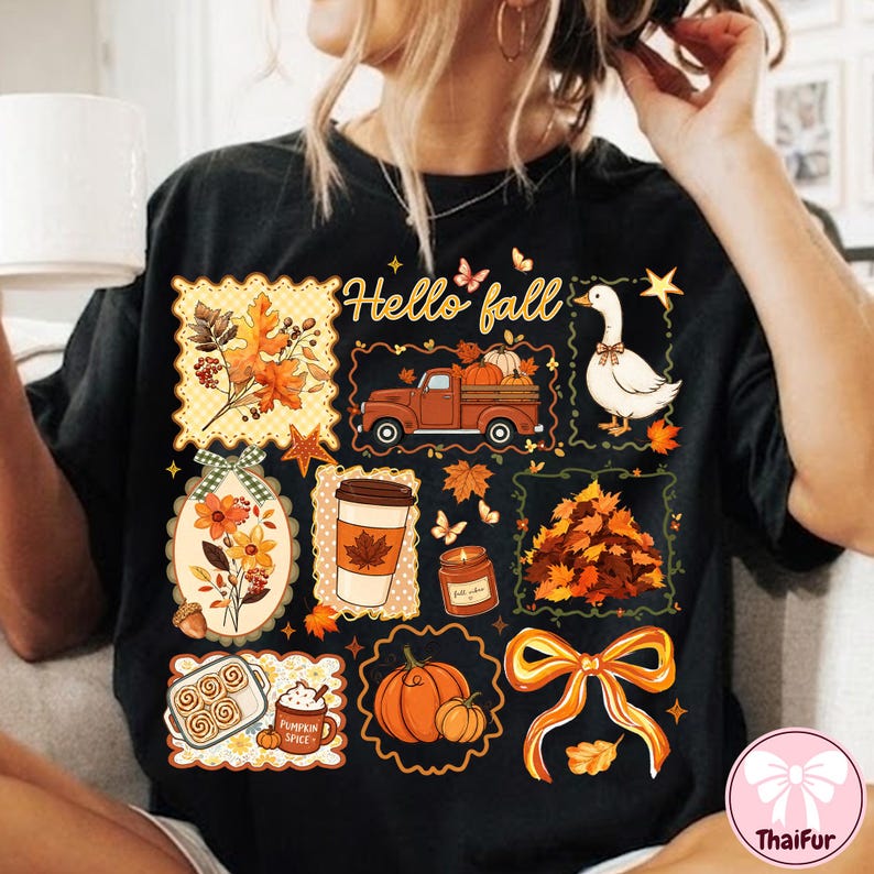 May include: A black t-shirt featuring a graphic print with the text Hello fall. The design includes a truck, a goose, a coffee cup, a candle, pumpkins, a pile of leaves, cinnamon rolls, a bow, and floral elements in orange, yellow, and brown.