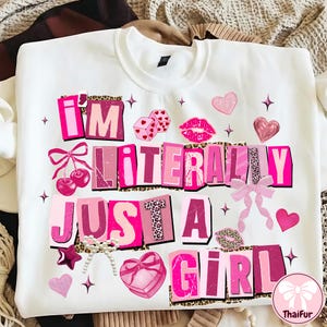 May include: White sweatshirt with the text "I'M LITERALLY JUST A GIRL" in pink, leopard print, and other decorative elements. The design includes cherries, dice, lips, hearts, and bows.