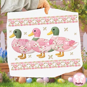 May include: A white decorative fabric featuring three patchwork ducks with pink, green, and white patterns. The ducks have yellow beaks and feet. The fabric has a border of hearts and floral designs, with a ThaiFur logo in the bottom right corner.