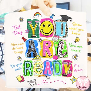May include: White fabric with the words "YOU ARE READY" in colorful, block letters. The design includes a smiley face, a graduation cap, a rainbow, and other school-themed graphics. Text includes "Test Day" and "You can do hard things."