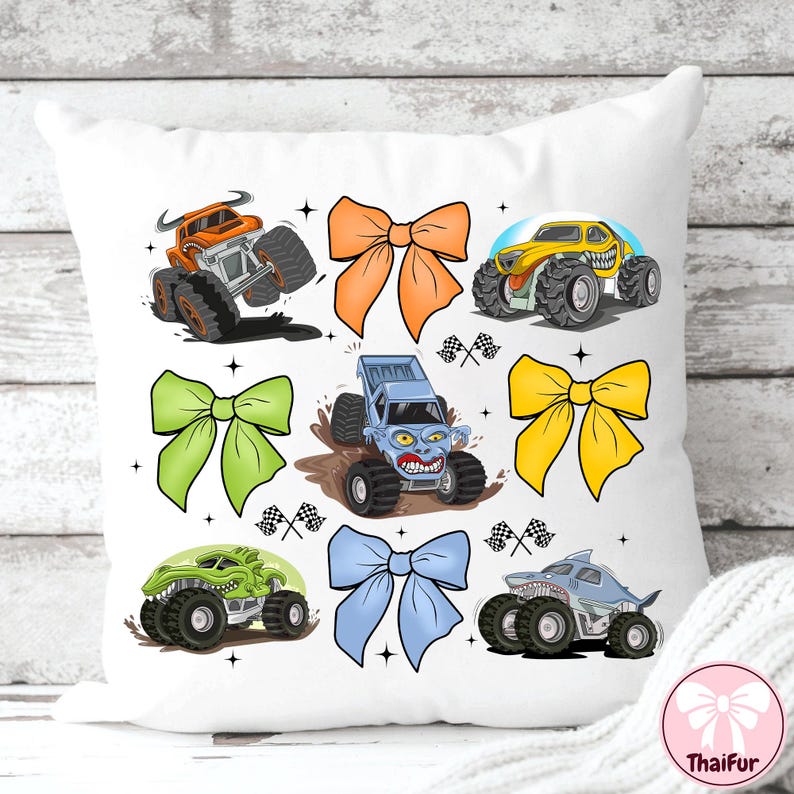 K&ouml;nnte beinhalten: Wei&szlig;es Kissen mit bunten Monster-Truck-Illustrationen und gro&szlig;en Schleifen. Die Trucks sind orange, gelb, gr&uuml;n und blau, mit schwarzen Reifen. Die Schleifen sind orange, gr&uuml;n, gelb und blau. Dekoratives Design.