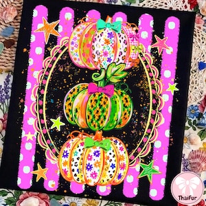 May include: A black rectangular print featuring three stacked pumpkins decorated with floral and leopard patterns, accented by small bows. The design is framed by a gold scalloped oval and set against a background of vertical pink polka-dot stripes.