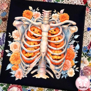 May include: A black fabric print featuring a human rib cage illustration containing four carved orange jack-o'-lanterns. The skeletal structure is surrounded by a vibrant arrangement of orange, peach, and white flowers with blue-tinted leaves.