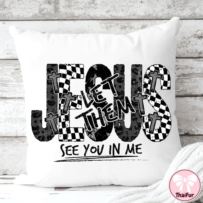 May include: White decorative pillow with the words "JESUS LET THEM SEE YOU IN ME" in black. The word "JESUS" is in a checkered pattern, and the word "THEM" is in a leopard print. Small crosses are incorporated into the design.