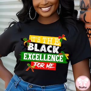May include: Black t-shirt with the text "IT'S THE BLACK EXCELLENCE FOR ME" in white, yellow, green, and red. The design includes decorative ribbons. The shirt is worn with blue jeans.