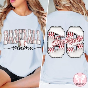 May include: Pale blue t-shirt featuring the text "BASEBALL mama" and a baseball graphic. The back displays the name "Jackson" and the number "68" in a baseball design. A baseball-themed shirt.