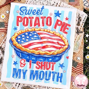 May include: White t-shirt with a patriotic design featuring a sweet potato pie decorated as an American flag. The text reads "Sweet Potato Pie & I Shut My Mouth" in red and blue. The design includes stars and stripes.
