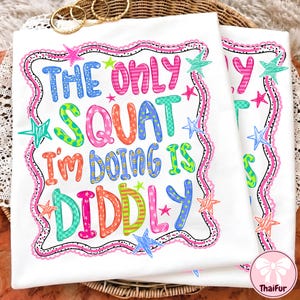 May include: A white t-shirt featuring a colorful graphic with the text "THE ONLY SQUAT I'M DOING IS DIDDLY" in various bright colors and patterns. The design is surrounded by a wavy pink border and several multi-colored star illustrations.