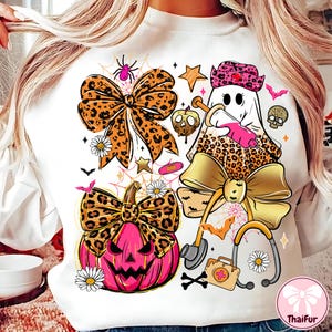 May include: White sweatshirt with a Halloween-themed graphic. The design includes a ghost nurse, a pink jack-o'-lantern, bows with leopard print, bats, stars, and medical-themed elements. The overall theme is a blend of Halloween and medical motifs.