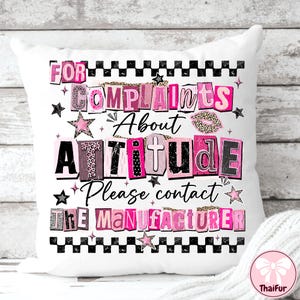 May include: White decorative pillow with the text "FOR COMPLAINTS About ATTITUDE Please contact THE MANUFACTURER" in pink, black, and leopard print lettering. The pillow has a black and white checkered border and star accents.