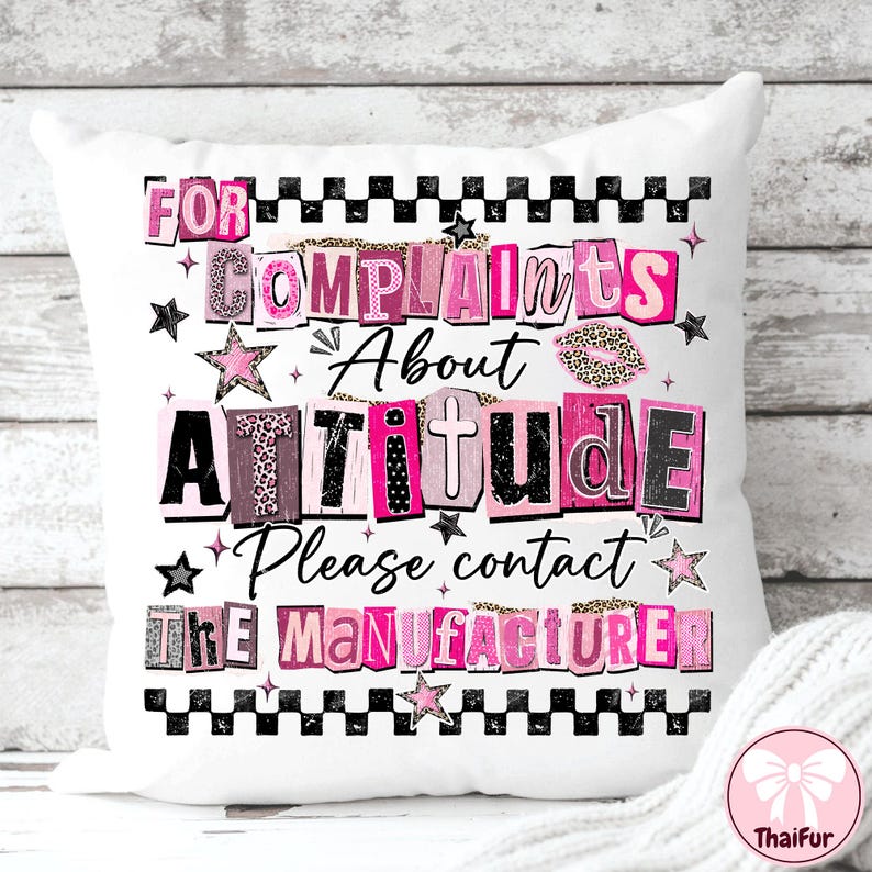 May include: White decorative pillow with the text "FOR COMPLAINTS About ATTITUDE Please contact THE MANUFACTURER" in pink, black, and leopard print lettering. The pillow has a black and white checkered border and star accents.