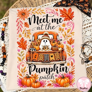 May include: A cream-colored t-shirt featuring a graphic of an orange pickup truck filled with pumpkins and a ghost wearing a beanie. The text reads Meet me at the Pumpkin patch. The design is surrounded by colorful autumn leaves, flowers, and candy corn.
