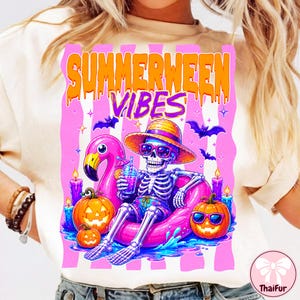Peut inclure: T-shirt crème avec un graphisme coloré. Le motif représente un squelette portant des lunettes de soleil et un chapeau, se relaxant sur une bouée flamant rose. Le texte "SUMMERWEEN VIBES" est au-dessus du squelette, avec des citrouilles et des chauves-souris.