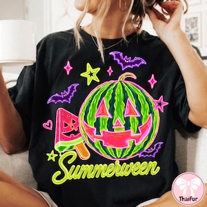 May include: Black t-shirt with a neon green and pink watermelon jack-o'-lantern design, a watermelon popsicle, and purple bats and stars. The text "Summerween" is in neon green script.