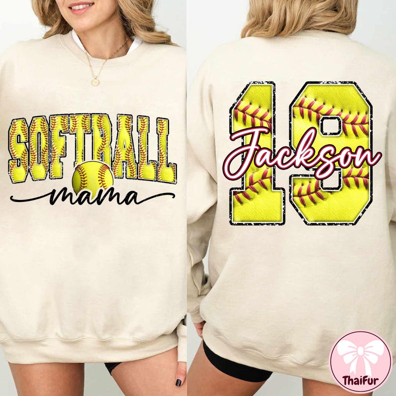 Op de afbeelding: Cr&egrave;mekleurige sweatshirt met de tekst "SOFTBALL mama" en een softbalafbeelding op de voorkant. De achterkant heeft het nummer 19 met een softbalontwerp en de naam "Jackson". Een casual, sportief kledingstuk.