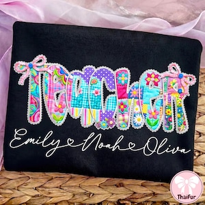 Pode incluir: Camiseta preta com a palavra "TEACHER" em letras de patchwork coloridas. Os nomes "Emily", "Noah" e "Oliva" estão escritos abaixo em escrita branca. O design inclui laços cor-de-rosa na parte superior da palavra "TEACHER".