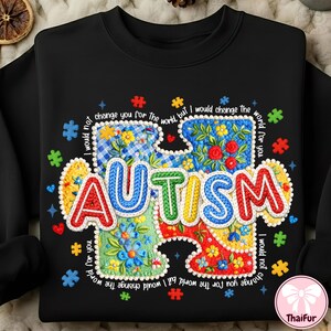 May include: Black sweatshirt featuring a colourful puzzle piece design with the word "AUTISM". The puzzle piece is filled with floral patterns and surrounded by the text "I would not change you for the world, but I would change the world for you."