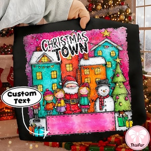 Może przedstawiać: Czarna poduszka z kolorową ilustracją świątecznego miasteczka. Projekt przedstawia domy, choinkę, Świętego Mikołaja i napis "CHRISTMAS TOWN". Różowy baner jest dołączony do niestandardowego tekstu.