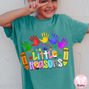 May include: Teal t-shirt with a colorful graphic featuring handprints, crayons, and the text "Little Reasons." The design includes the phrase "I love my job for all the." The shirt has a relaxed fit and short sleeves.