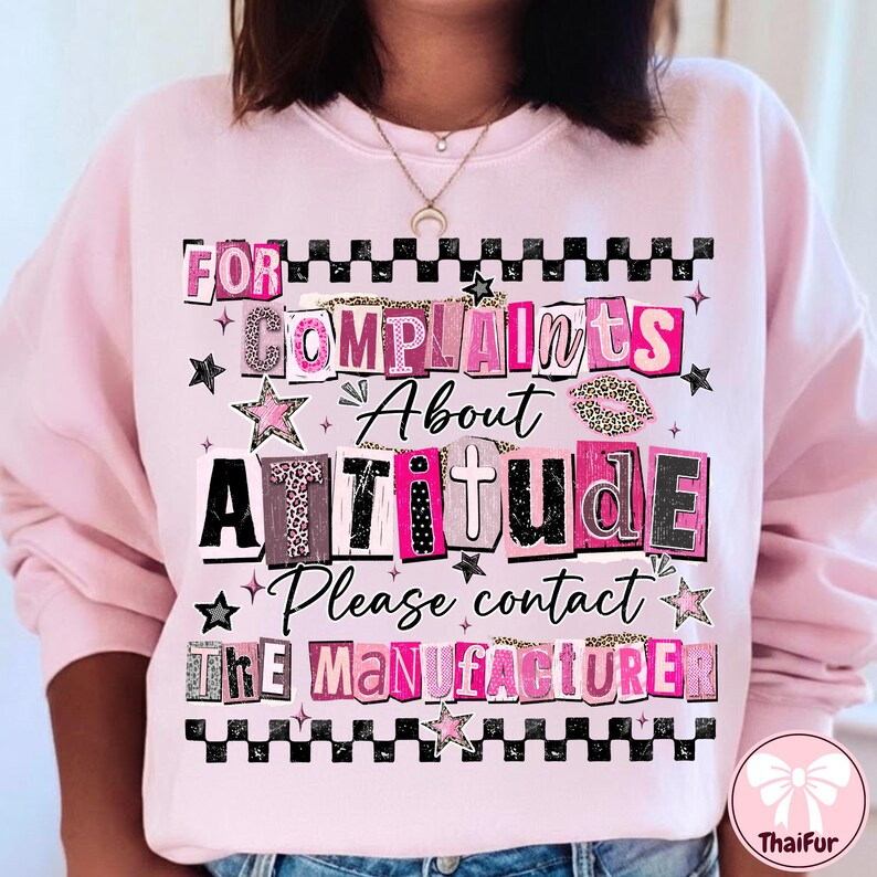 May include: Pink sweatshirt with the text "FOR COMPLAINTS ABOUT ATTITUDE Please contact THE MANUFACTURER" in a mix of fonts and patterns, including leopard print and stars. The design is framed with a black and white checkered pattern.