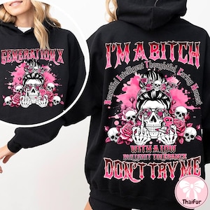 Puede incluir: Sudadera con capucha negra con un diseño gráfico de una calavera con gafas de sol, rodeada de rosas y calaveras. El texto "GENERATION X" está en la parte delantera y "I'M A BITCH" y "DON'T TRY ME" en la trasera.