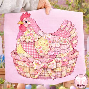 May include: A pink fabric hen in a basket design. The hen is made of patchwork fabric with floral and gingham patterns. The basket has a large bow. The background is a solid pink color.