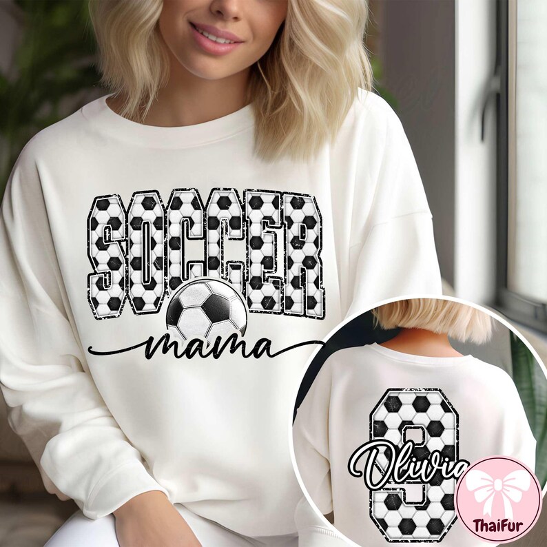 K&ouml;nnte beinhalten: Cremefarbenes Sweatshirt mit dem Schriftzug "SOCCER mama" im schwarz-wei&szlig;en Fu&szlig;ballmuster. Auf der R&uuml;ckseite ist die Zahl 8 und der Name "Olivia" im passenden Fu&szlig;ball-Design zu sehen.