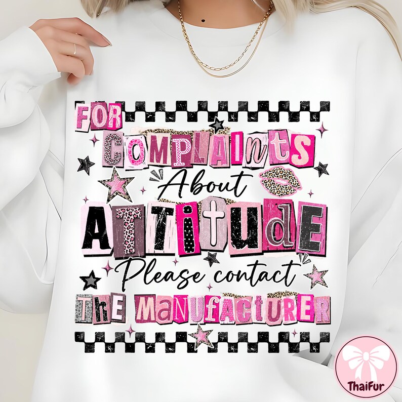 May include: White sweatshirt with the text "FOR COMPLAINTS ABOUT ATTITUDE Please contact THE MANUFACTURER" in pink, black, and leopard print lettering. The design includes stars and a checkered border.
