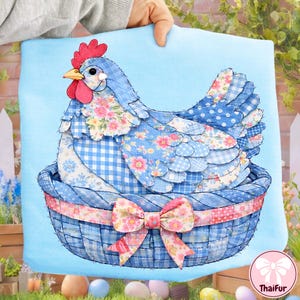 May include: A blue decorative pillow featuring a patchwork chicken design. The chicken is composed of various blue patterned fabrics, including floral, gingham, and polka dots. It sits in a blue basket with a pink floral bow. The background is a light blue.