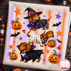 May include: A white fabric square featuring a Halloween-themed print of three dachshunds dressed in costumes. One wears a witch hat and cape, one is wrapped like a mummy holding a pumpkin bucket, and one wears a vampire cape. Includes pumpkins and bats.
