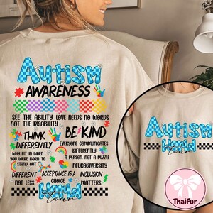 Puede incluir: Una sudadera beige con un diseño a cuadros azules y blancos y el texto "Autism Awareness" en azul. El texto "See the ability love needs no words not the disability" está debajo del diseño a cuadros. El texto "Think Differently Be Kind" está debajo de eso. El texto "Everyone communicates differently a person not a puzzle Neurodiversity" está debajo de eso. El texto "Different Acceptance is a Inclusion Not Less Choice Matters" está debajo de eso. El texto "Autism World" está debajo de eso. La sudadera tiene un lazo rosa en la esquina inferior derecha.