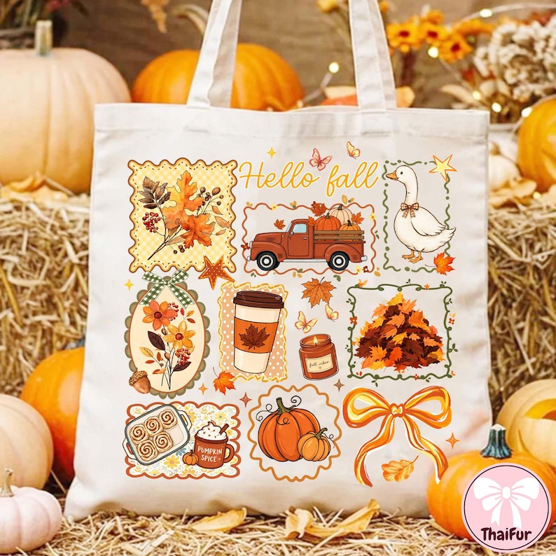 May include: A cream-colored canvas tote bag featuring a colorful autumn-themed graphic print. The design includes a truck, a goose, a coffee cup, a candle, pumpkins, a pile of leaves, a bow, and the text Hello fall in a decorative script.