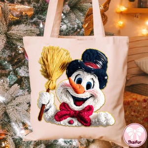 May include: A light pink tote bag with a smiling snowman design. The snowman has a carrot nose, blue eyes, and a red bow tie. He wears a black hat with a red band and holds a yellow broom. The bag has long handles.